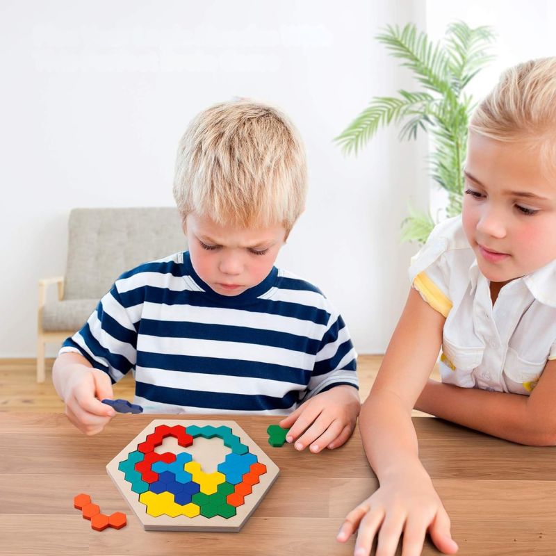 Deux enfants concentrés et complices qui jouent ensemble au puzzle hexagonal tangram bois - jeu éducatif logique enfant - Atelier Puzzle