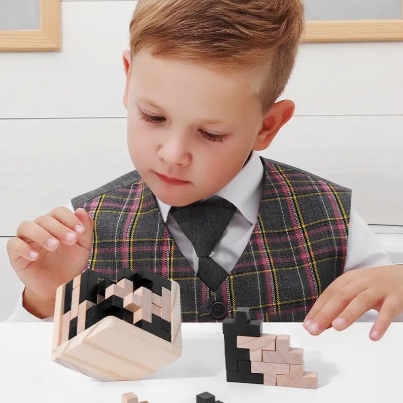 Garçon élégant très concentré qui assemble le puzzle cube 3D bois naturel noir défi intelligence enfant 6-10 ans - Atelier Puzzle