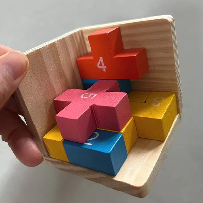 Gros plan main qui tient bloc bois jaune puzzle 3D coloré - qualité matériaux jouet enfant - Atelier Puzzle