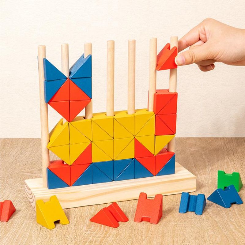 Gros plan main adulte qui place bloc rouge triangulaire sur tiges verticales bois structure colorée - motricité fine jeu éducatif - Atelier Puzzle