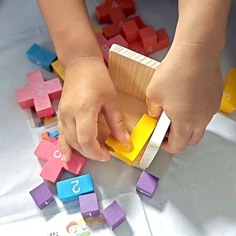 Mains enfant qui manipule blocs bois colorés puzzle 3D - jeu logique motricité fine enfant - Atelier Puzzle
